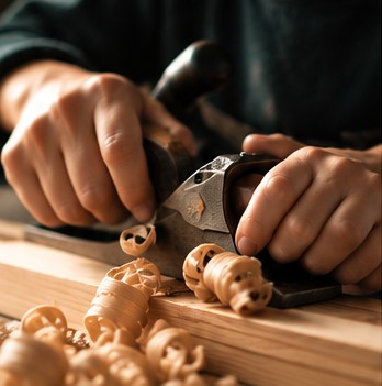 Hands planing a curl of wood